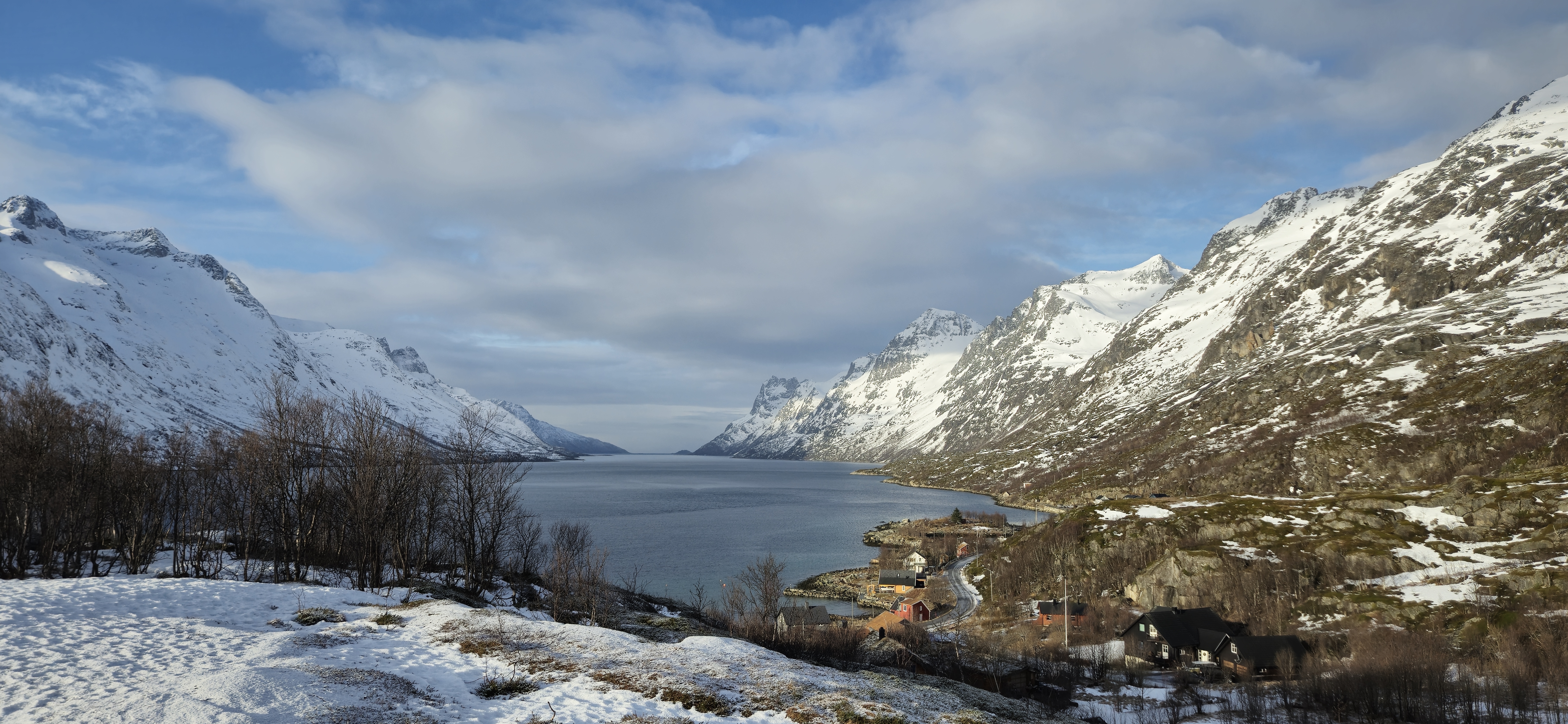 Ersfjordbotn, Norway - mountains to the left and right of the fjord with a small village in the distance.